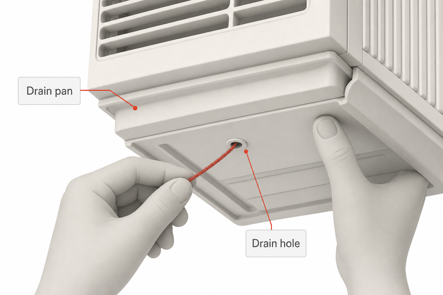 close-up of hands using a thin wire or pipe cleaner to clear a small drain hole on the underside of a window air conditioner housing, with a shallow plastic drain pan visible above it
